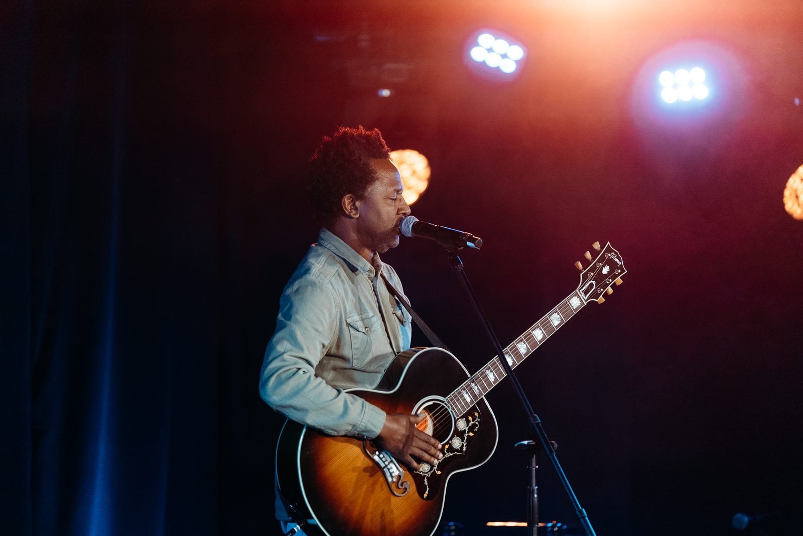 Musician singing on stage at an Unsung Hero benefit concert